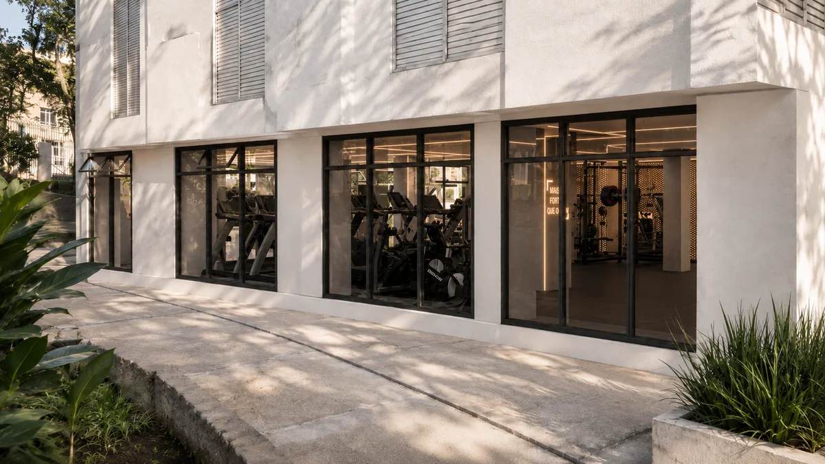 Fachada do espaço fitness com caixilharia em vidro e acesso ajardinado