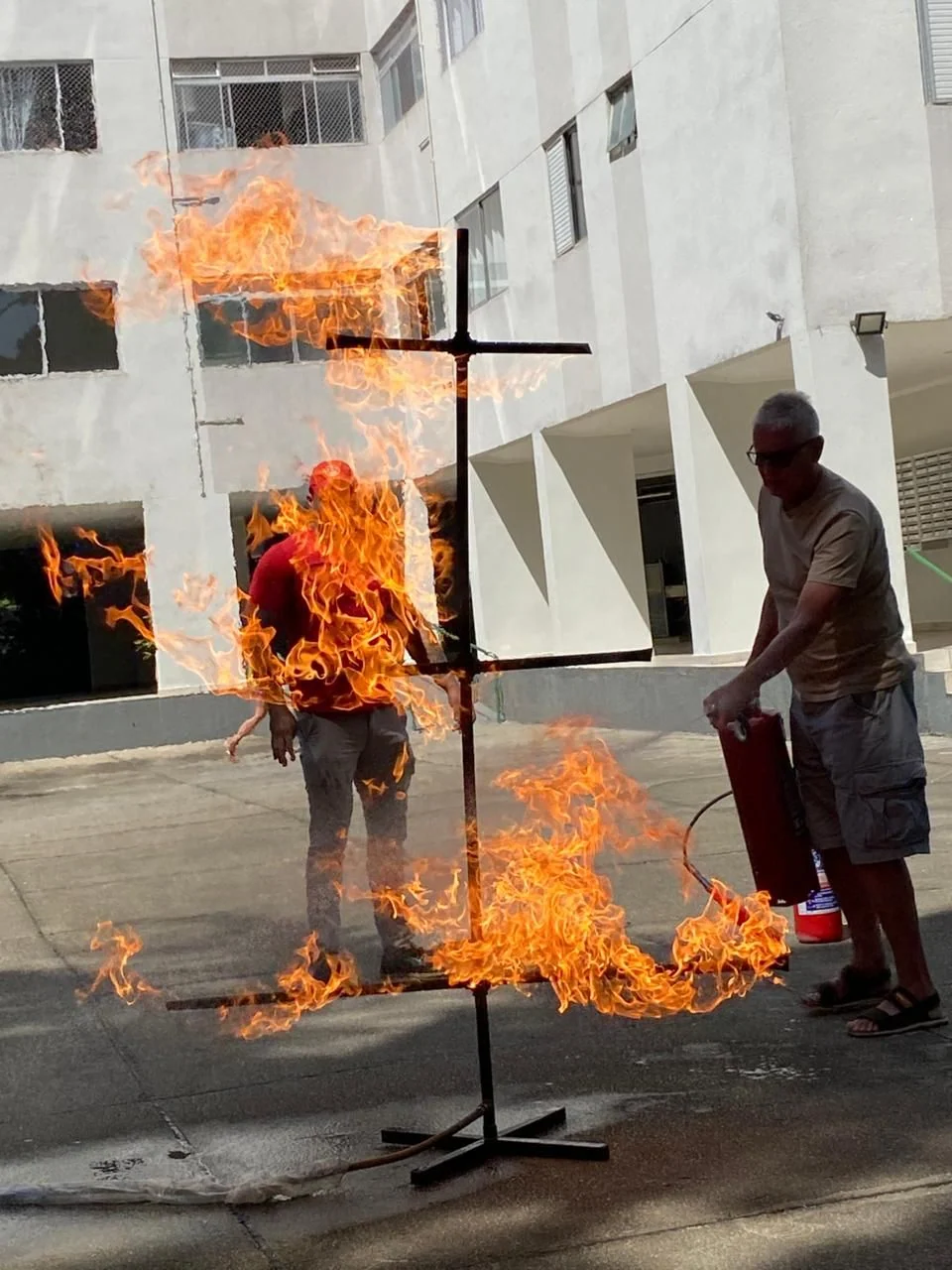 Participante combatendo foco de incêndio com extintor em área externa de edificação